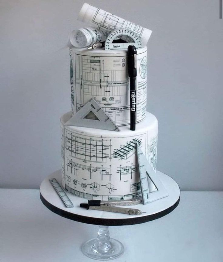 a three tiered cake decorated with architectural drawings and writing on it's sides