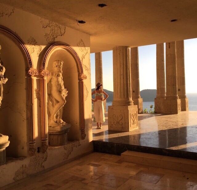 the interior of a building with columns and statues on display in front of large windows