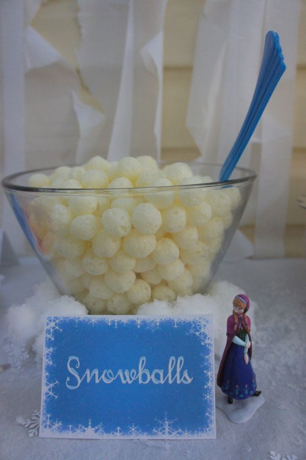 a bowl filled with snowballs next to a small figurine on top of a table