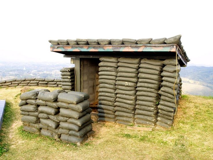 a pile of sand bags sitting on top of a grass covered field next to a building