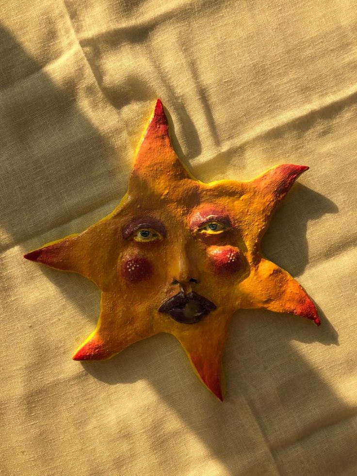 a yellow and red sun face on a white sheet