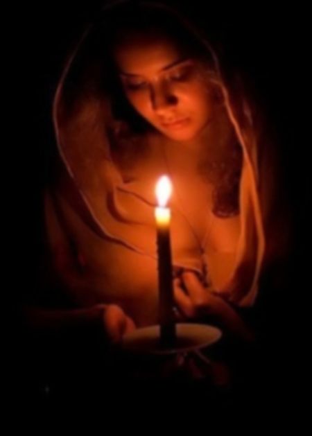 a woman holding a lit candle in her hands