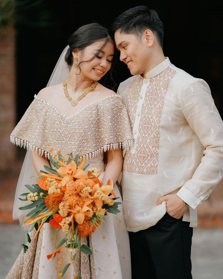 a man and woman standing next to each other in front of a building with flowers