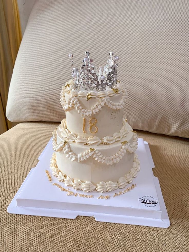 a three tiered cake sitting on top of a white tray with a crown on top