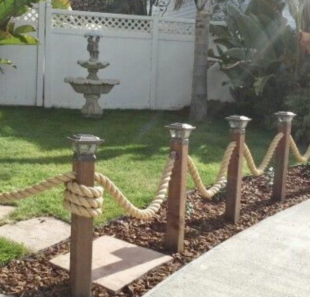 a roped off area in front of a white fence with fountain and water feature