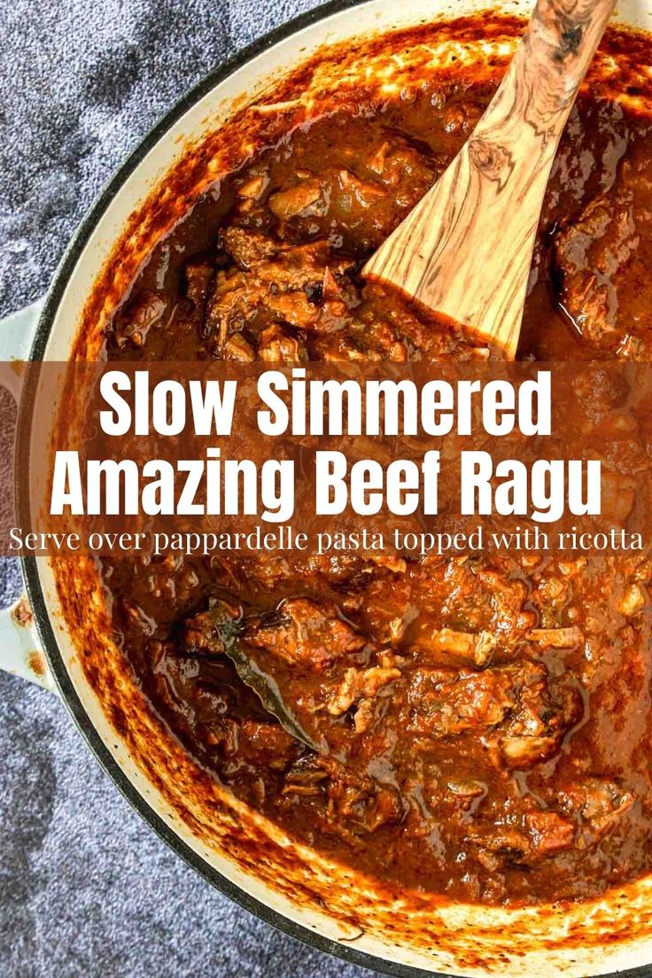 slow simmered beef ragu in a pot with a wooden spoon on the side