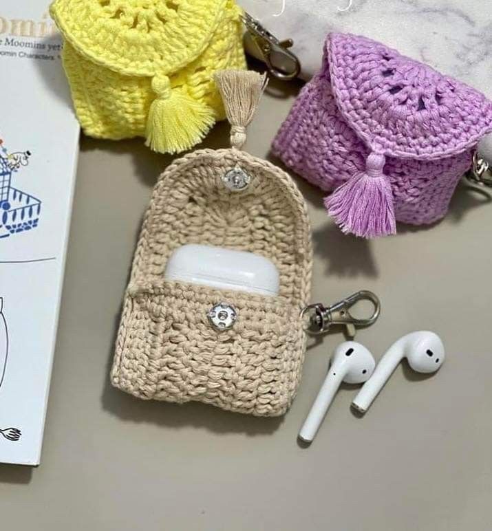 three crocheted purses and earbuds laying on top of a table