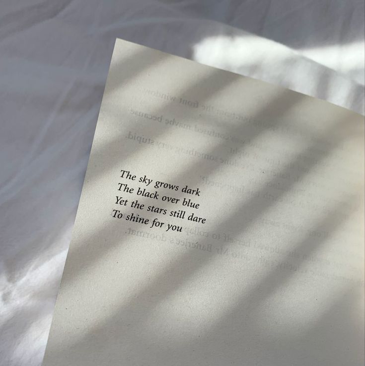 an open book sitting on top of a bed next to a white sheet with the words, the sky grows dark