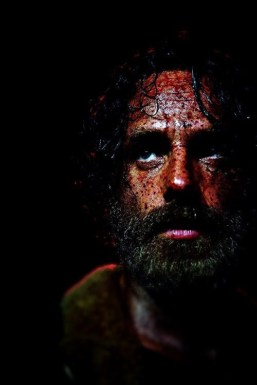 a man with long hair and beards covered in mud, staring at the camera