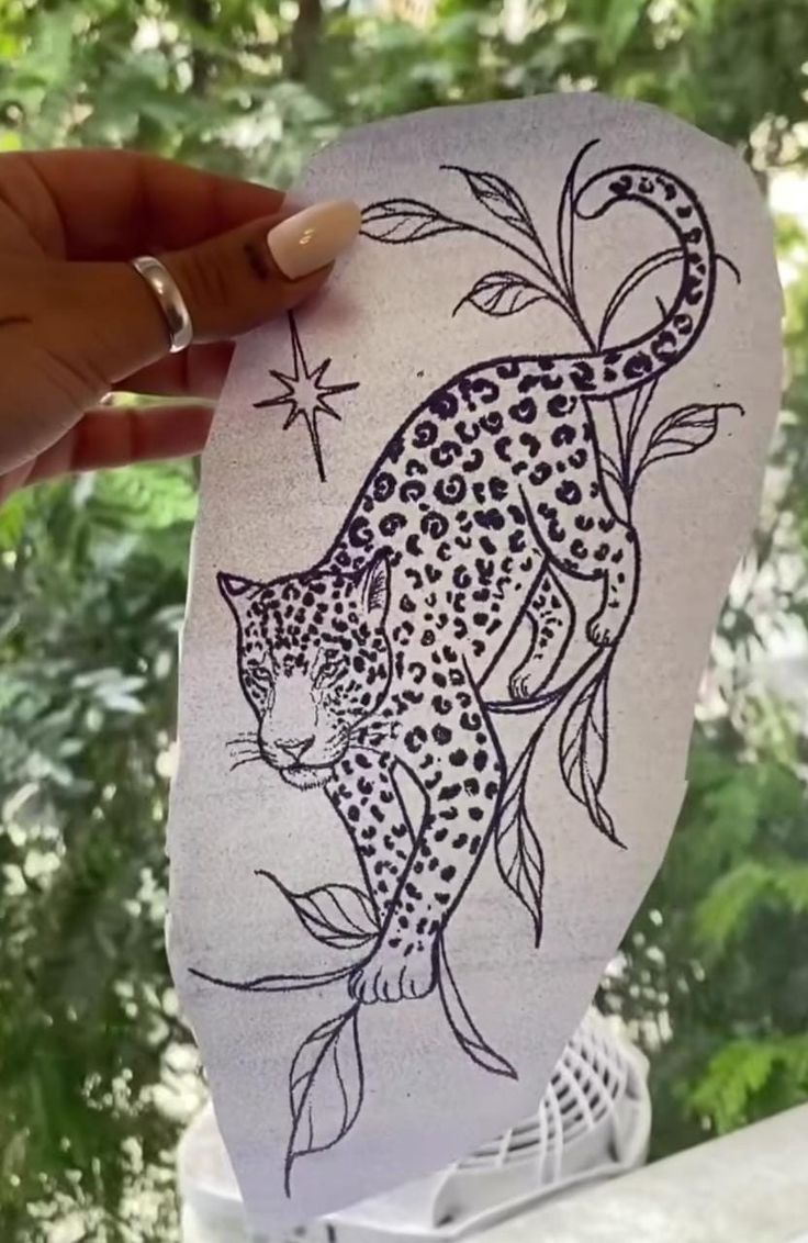 someone holding up a paper cutout with a drawing of a leopard on it