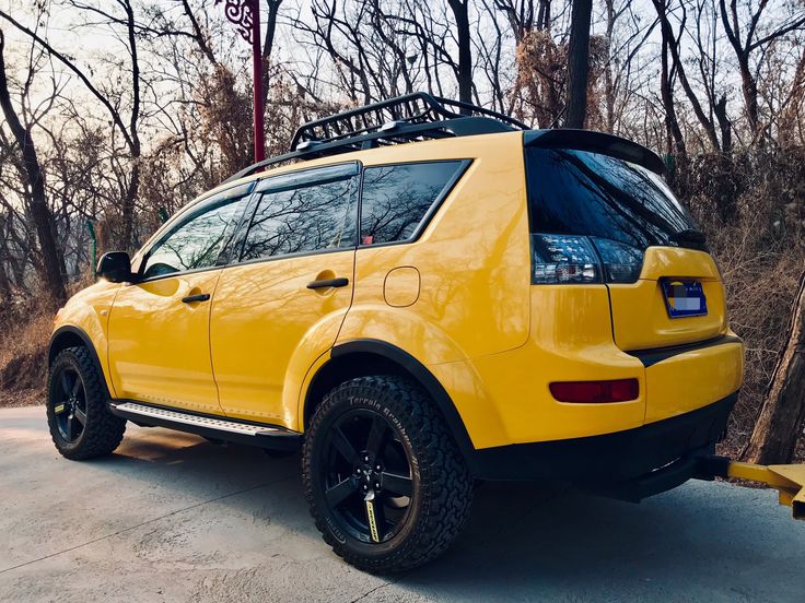 a yellow suv parked in front of some trees