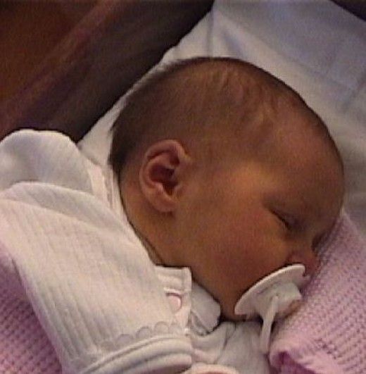 a baby wrapped in a pink blanket sleeping on top of a white pillow with its eyes closed