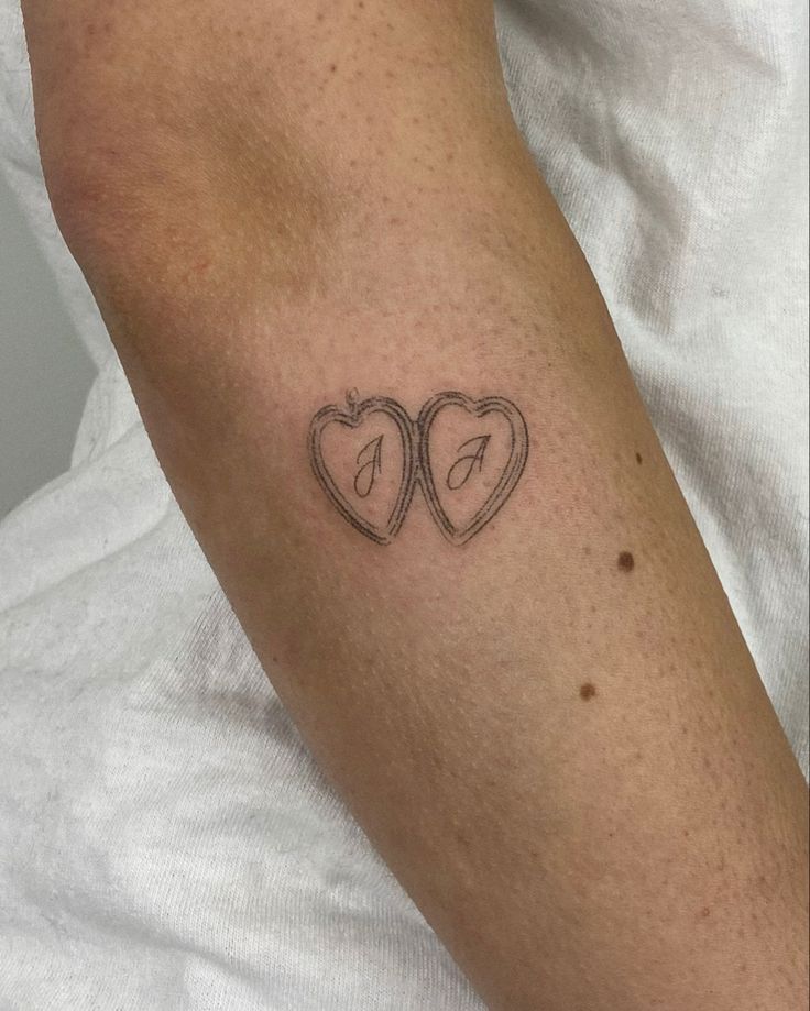 two hearts with an arrow tattoo on the arm