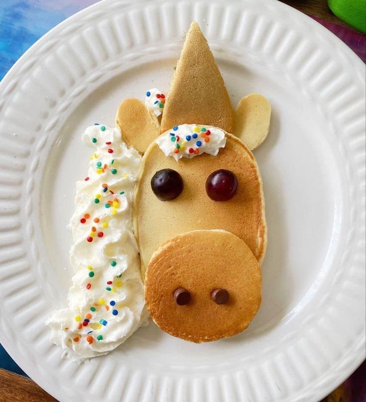 a white plate topped with pancakes covered in icing and a giraffe face