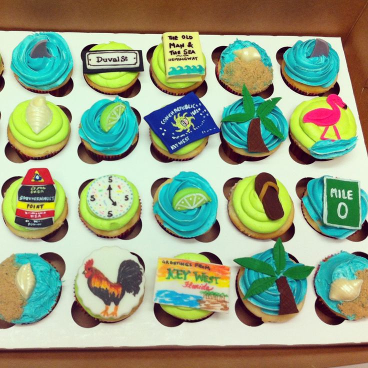 cupcakes in a box decorated with different types of frosting and beach themed decorations