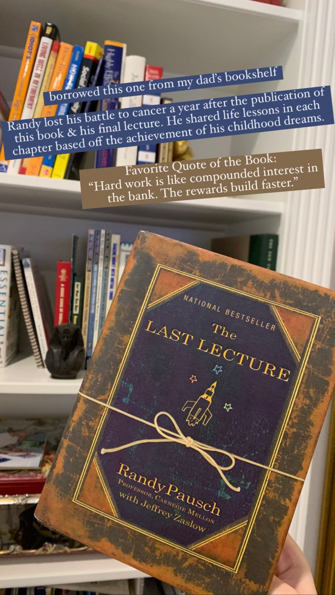 a person holding up a book in front of bookshelves