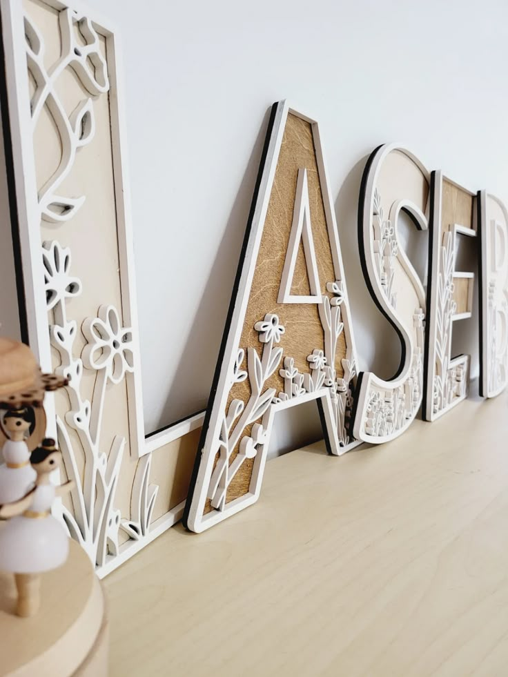 the letters are made out of wood and have floral designs on them, as well as flowers