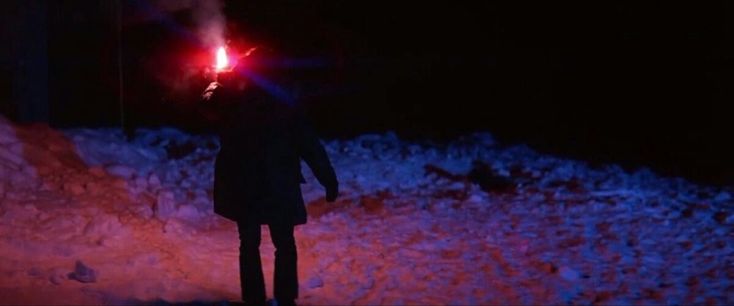 a person standing in the snow at night with a red light on their head and arms