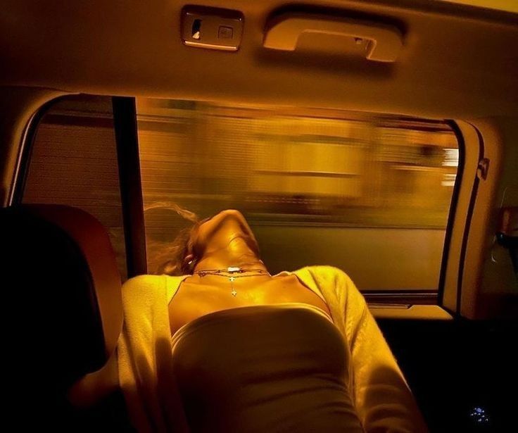 a woman laying down in the back seat of a car