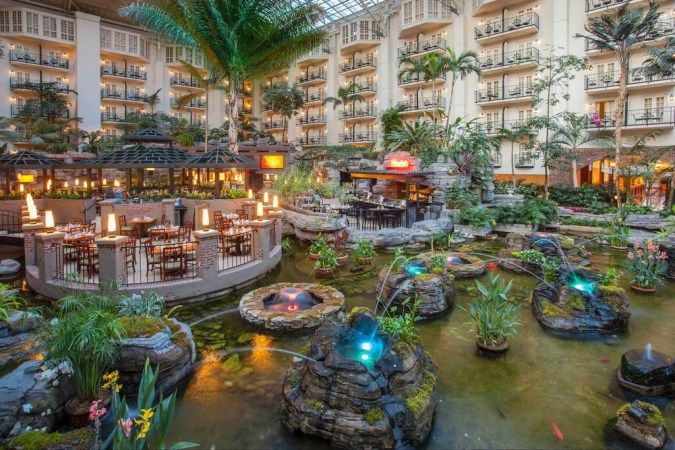 the inside of a building with many tables and chairs in front of an indoor waterfall