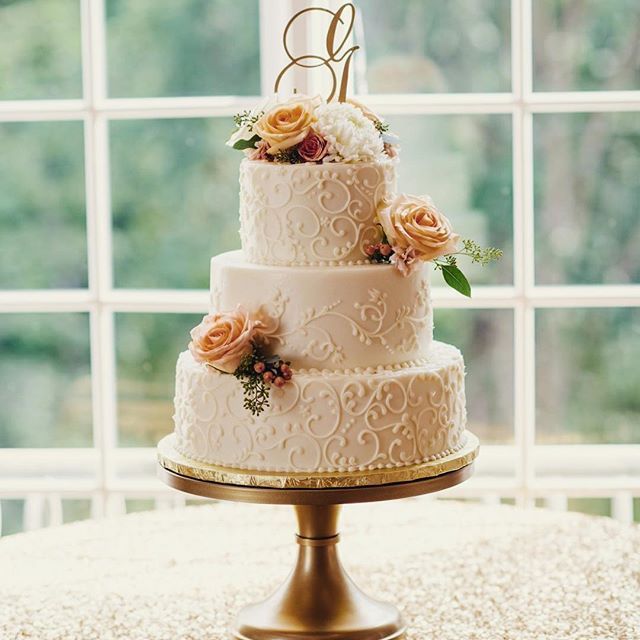 a three tiered wedding cake sitting on top of a table next to a window