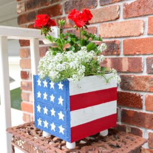 an american flag planter sitting on top of a wooden block with flowers in it