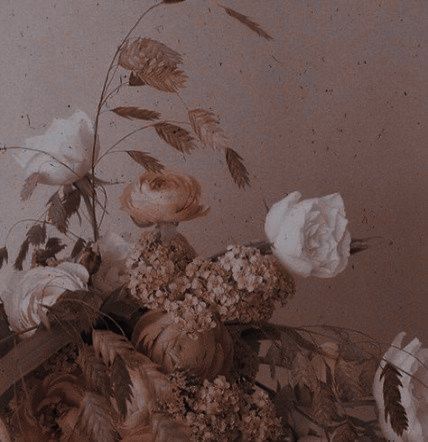 a vase filled with lots of flowers on top of a wooden table next to a wall