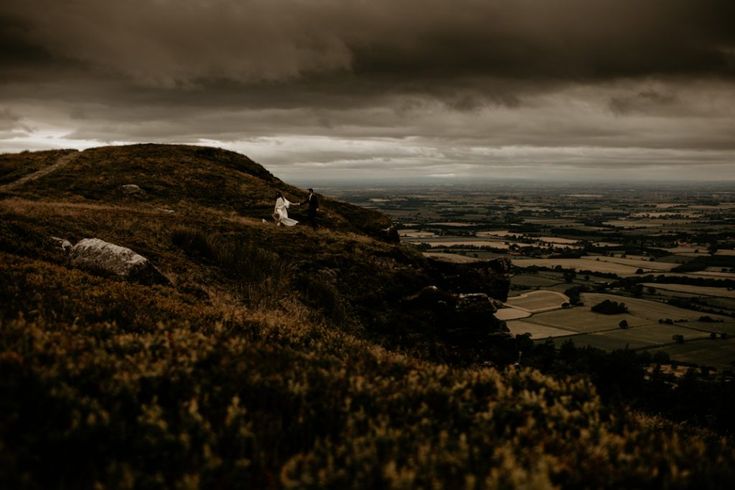 a person standing on top of a hill under a cloudy sky