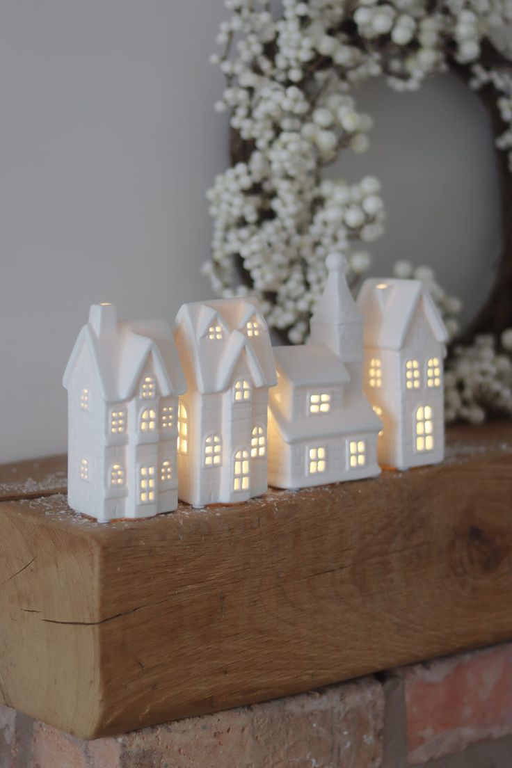 a group of white houses sitting on top of a wooden shelf next to a wreath