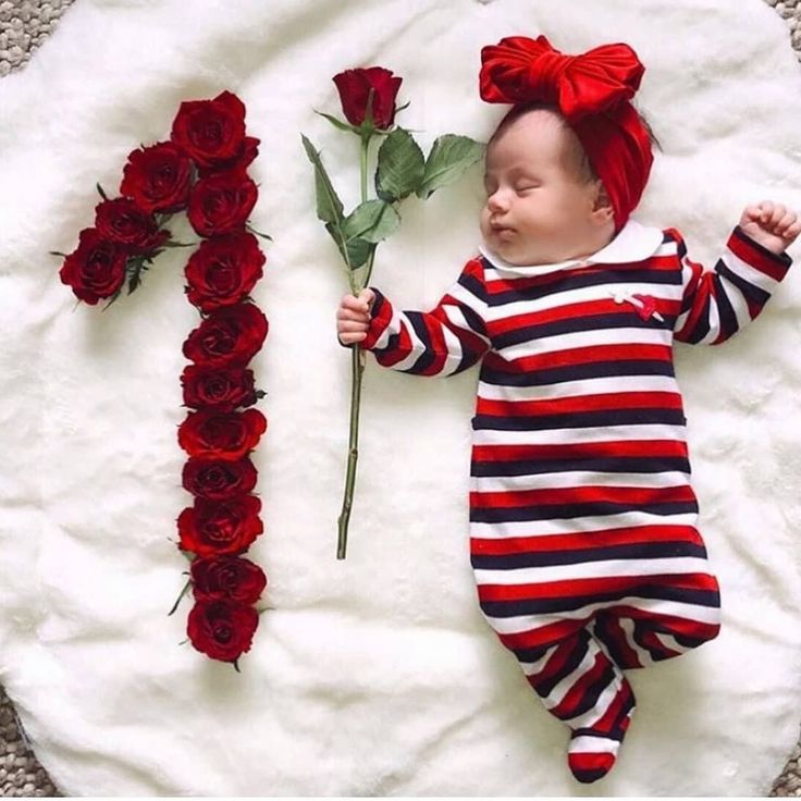 a baby is laying on the ground next to roses