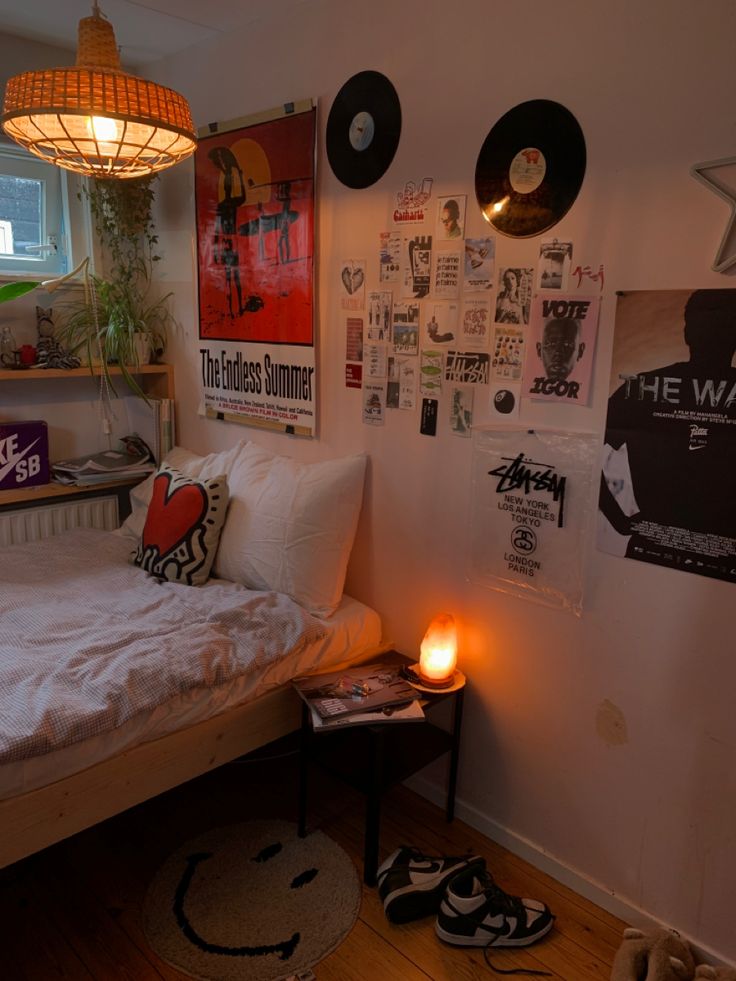 a bedroom with posters on the wall and a lit candle in front of the bed