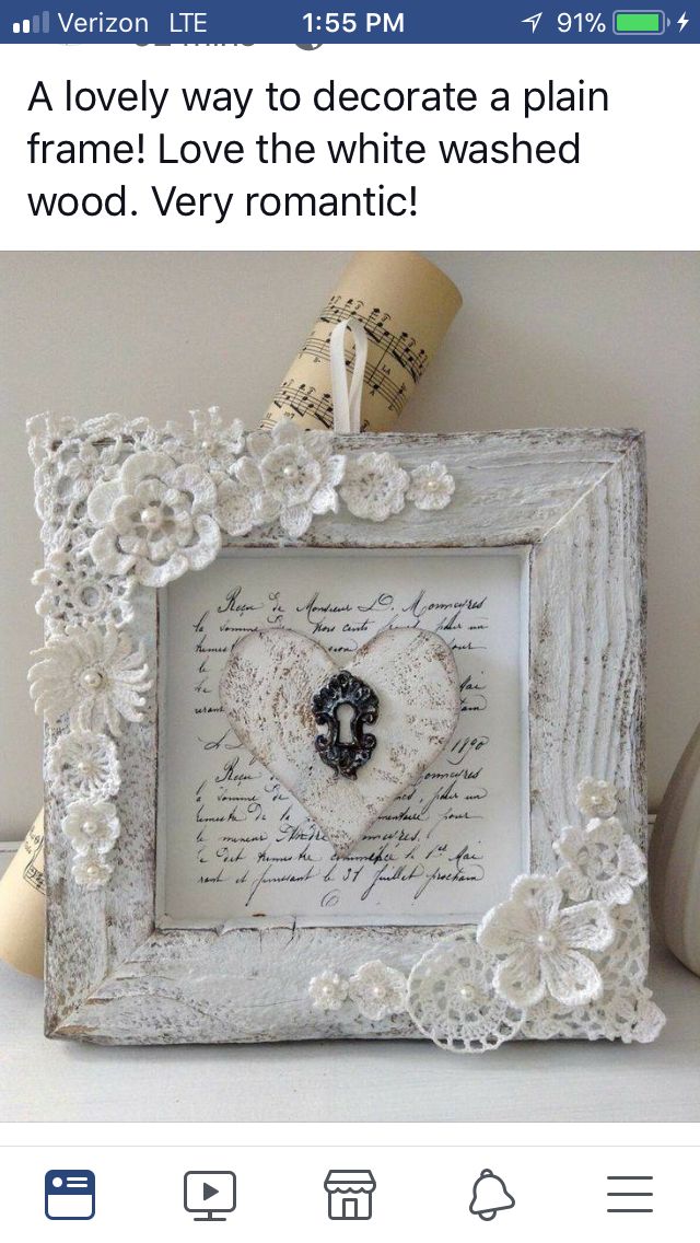 an old frame is decorated with white lace and paper flowers, as well as a heart