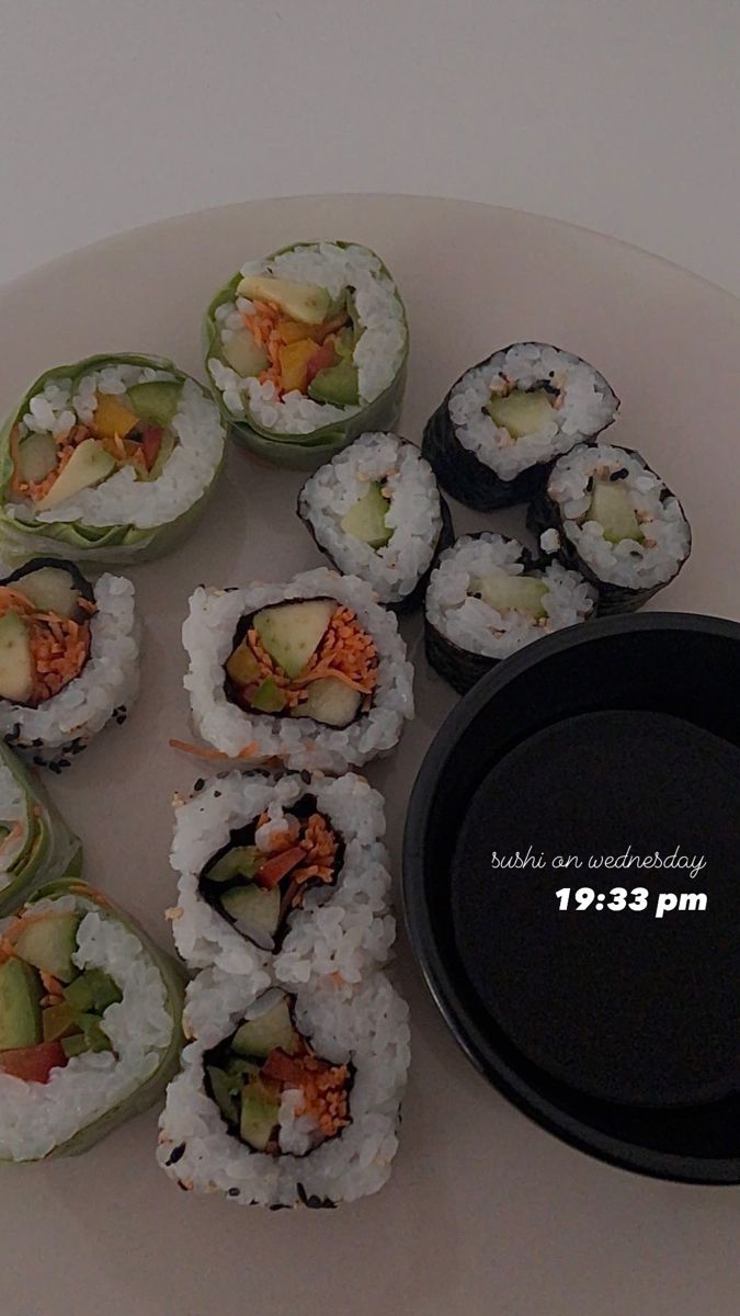 sushi rolls are arranged on a white plate with a black plastic container next to it