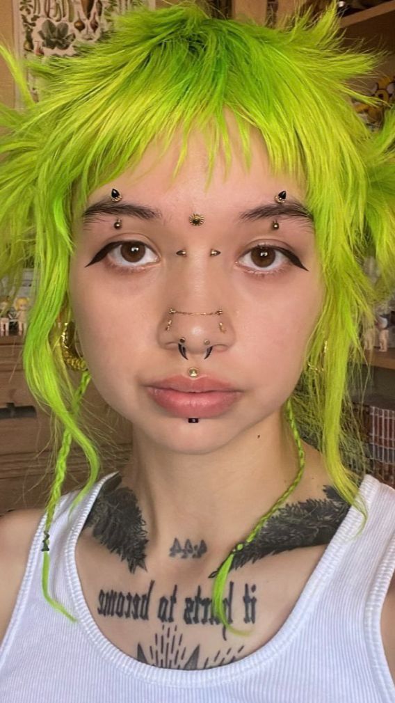 a woman with green hair and piercings on her face