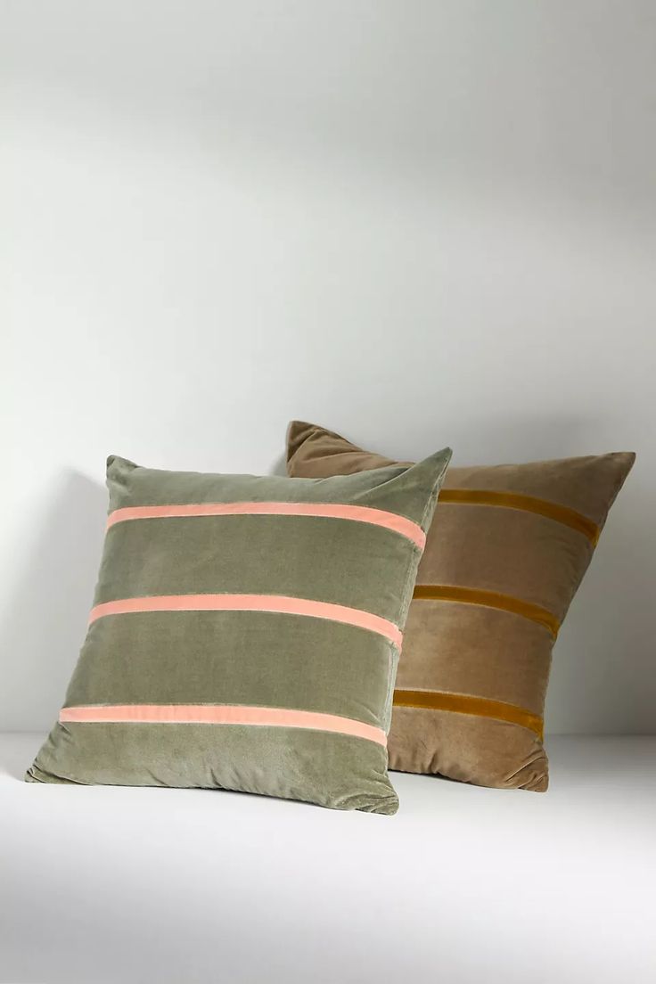 two pillows sitting on top of a bed next to each other in front of a white wall