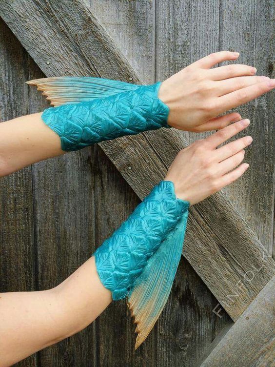 two hands are holding something in front of a wooden fence with blue fabric on it