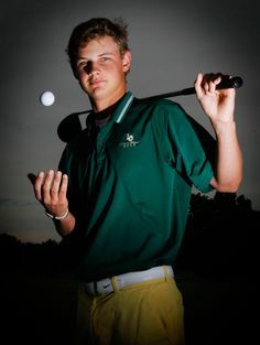 a young man holding a golf club and ball