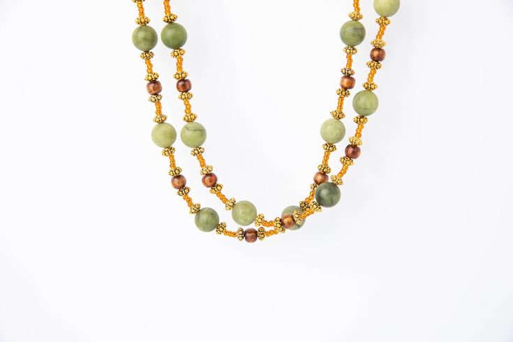 Weave your own history with the Green Jade Hanging. This stunning necklace is crafted of two long strands of matte green jade with gold coral, gold spacers and copper seed beads . Gold adjustable chain with lobster claw clasp. The gold tone chain and lobster claw clasp can be adjusted to your preferred length and worn as a choker or longer. It is also perfect for wearing in parties, wedding ceremonies and other formal occasions. Handmade Gold Jade Beaded Necklaces, Green Multi-strand Hand-strung Necklaces, Green Multi-strand Hand-strung Beaded Necklaces, Green Multi-strand Wooden Beads Jewelry, Elegant Green Beaded Necklaces With Wooden Beads, Elegant Green Beaded Necklace With Wooden Beads, Elegant Green Wooden Beaded Necklaces, Gold Double Strand Hand-strung Beaded Necklaces, Matte Green