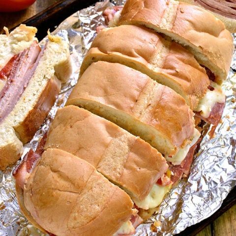 two sub sandwiches cut in half on tin foil