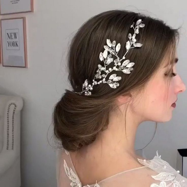 a woman wearing a bridal hair comb with leaves on it's head, in front of a white wall