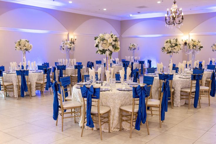 a room filled with lots of tables covered in blue and white cloths