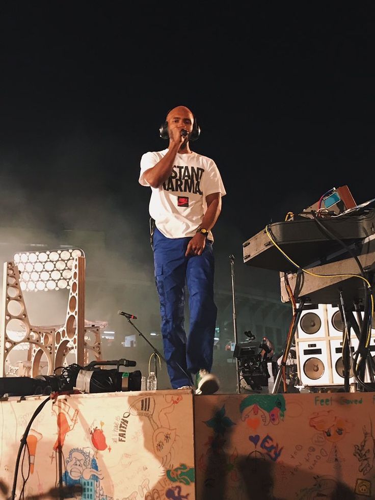 a man standing on top of a stage with headphones in his ears and microphone to his ear