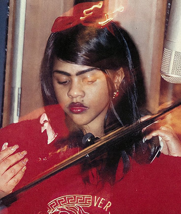 a woman in a red shirt holding a violin