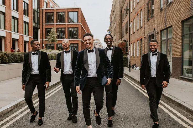 a group of men in tuxedos are walking down the street