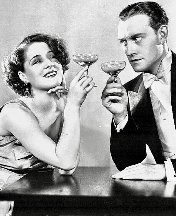 a man and woman sitting at a table holding wine glasses