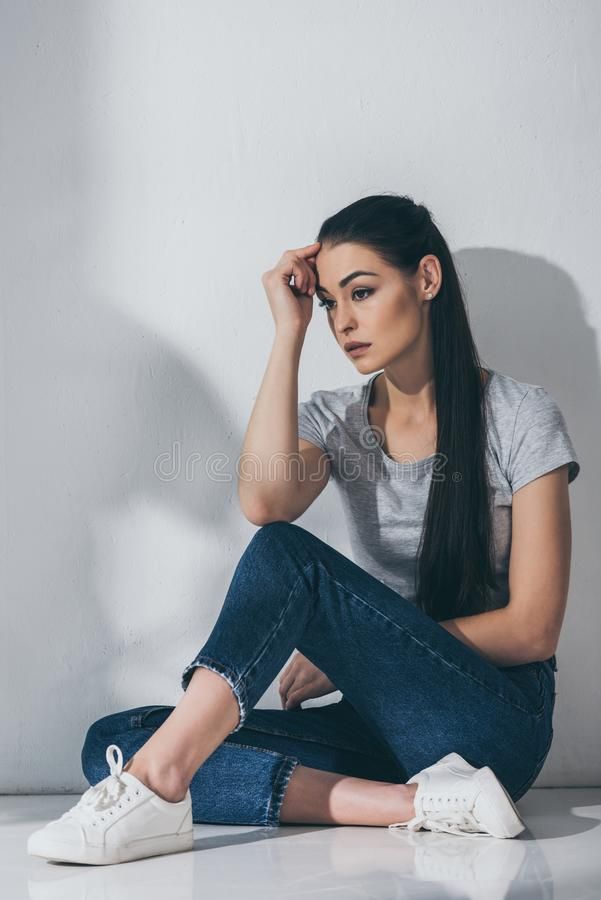 a young woman sitting on the floor with her hands behind her head and looking at the camera