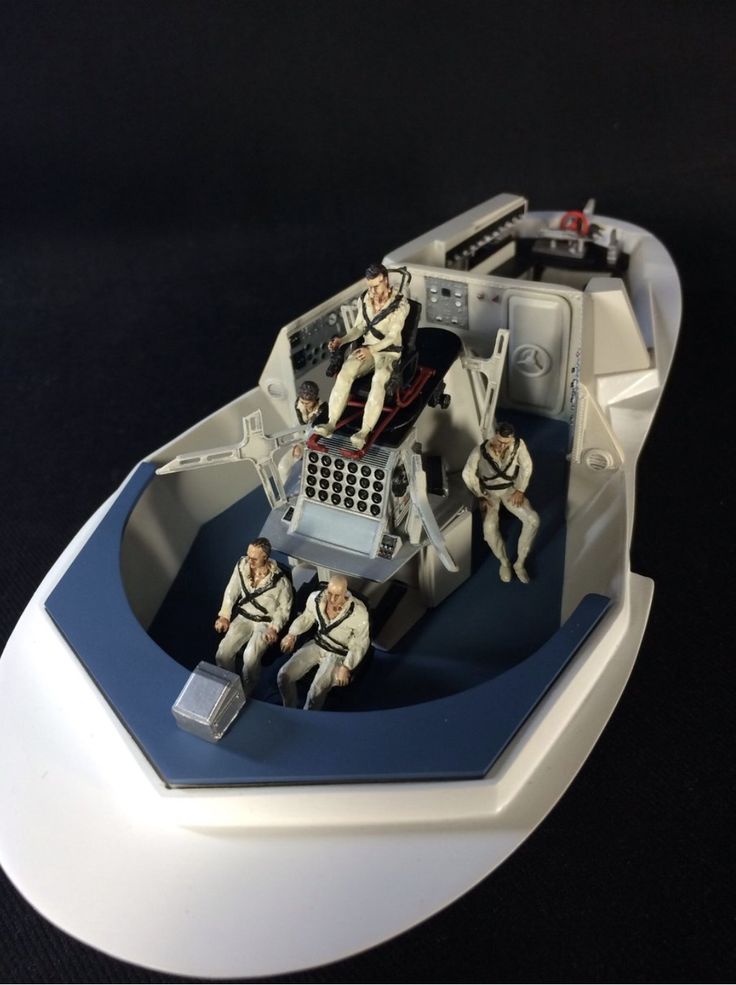 some toy soldiers are sitting in a small boat on a black surface with white trim