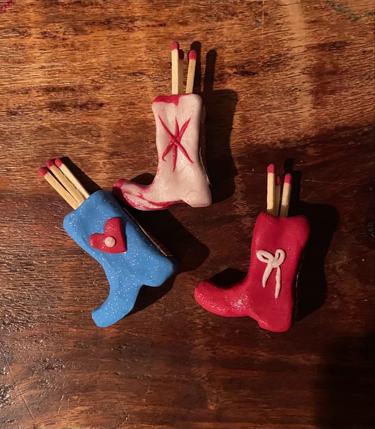 three miniature shoes with sticks sticking out of them sitting on a table next to each other