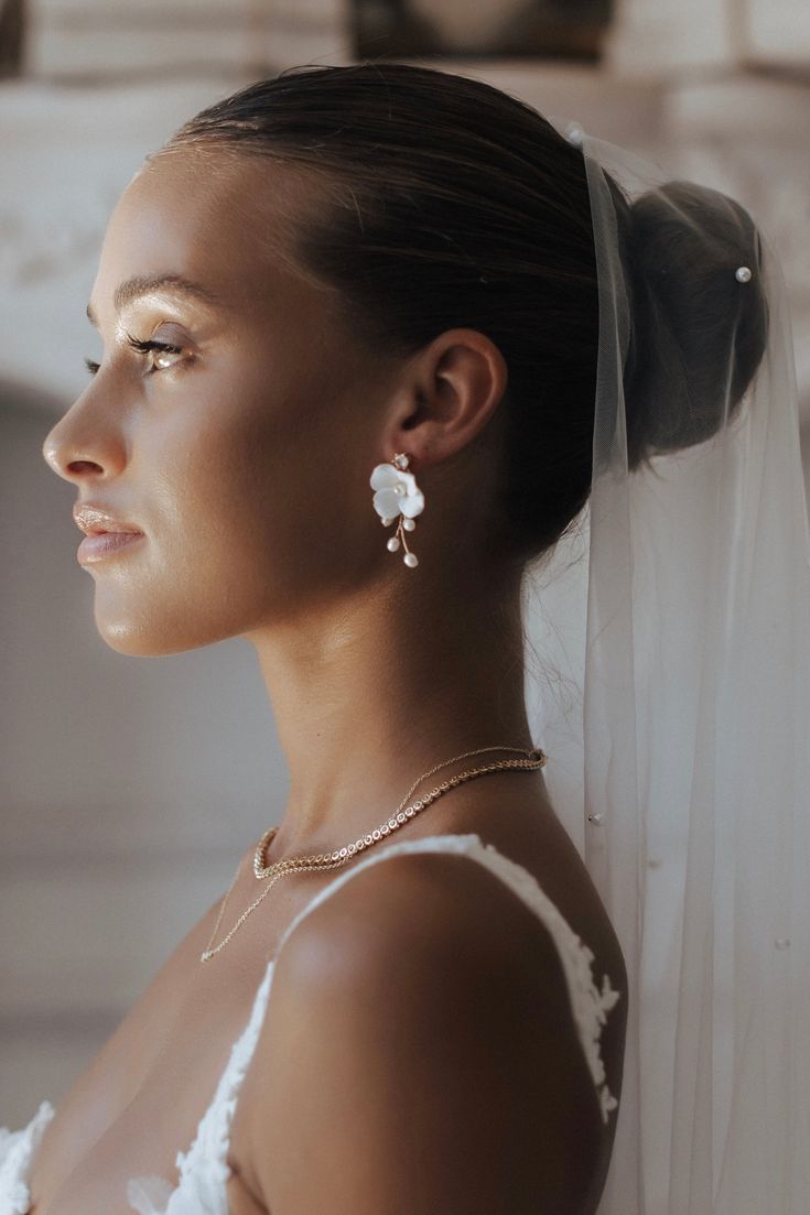 a woman in a wedding dress with a veil on her head looking off to the side