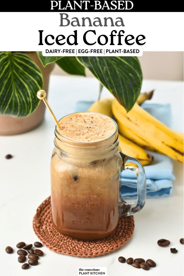 a glass jar filled with iced coffee sitting on top of a table next to bananas